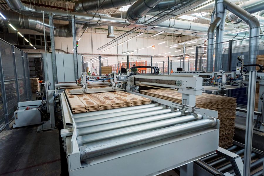 Roller conveyor and gantry with stacks of planks in a plant